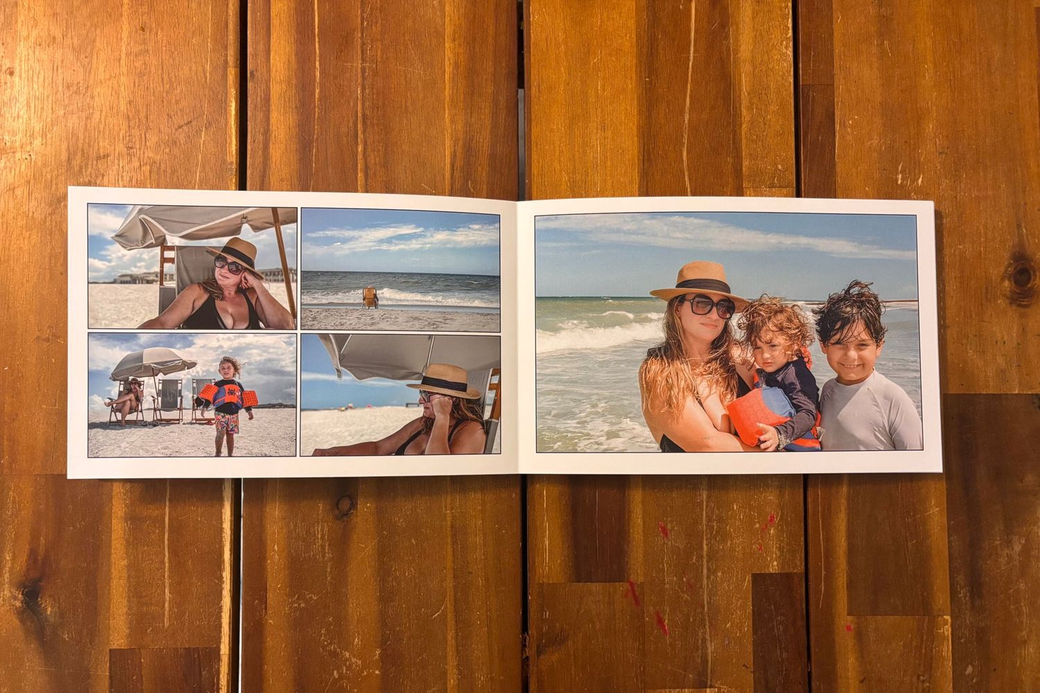 Open photo album displaying beach vacation photographs on wooden surface.