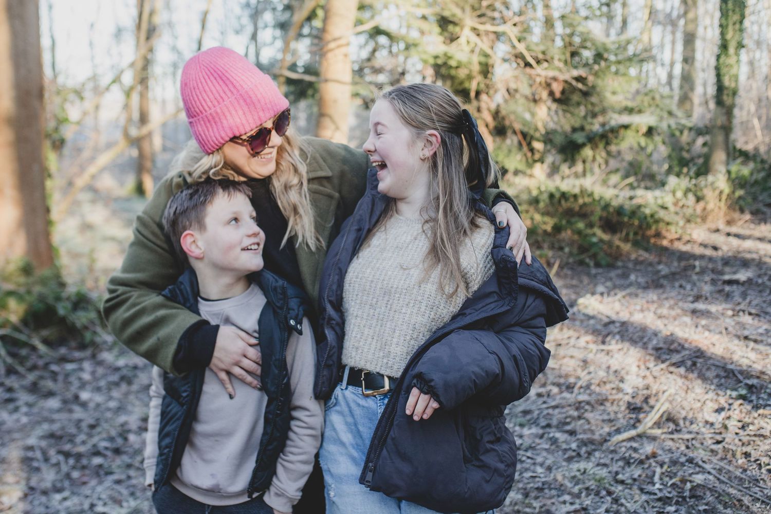 Three people share a candid moment together while hiking through a sunlit forest.
Family photography, Suffolk