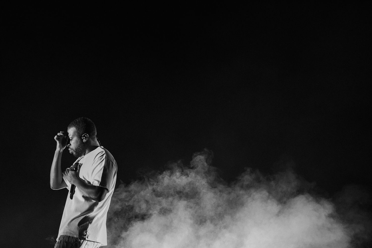 Dramatic black and white photo of a performer on stage surrounded by smoke effects.