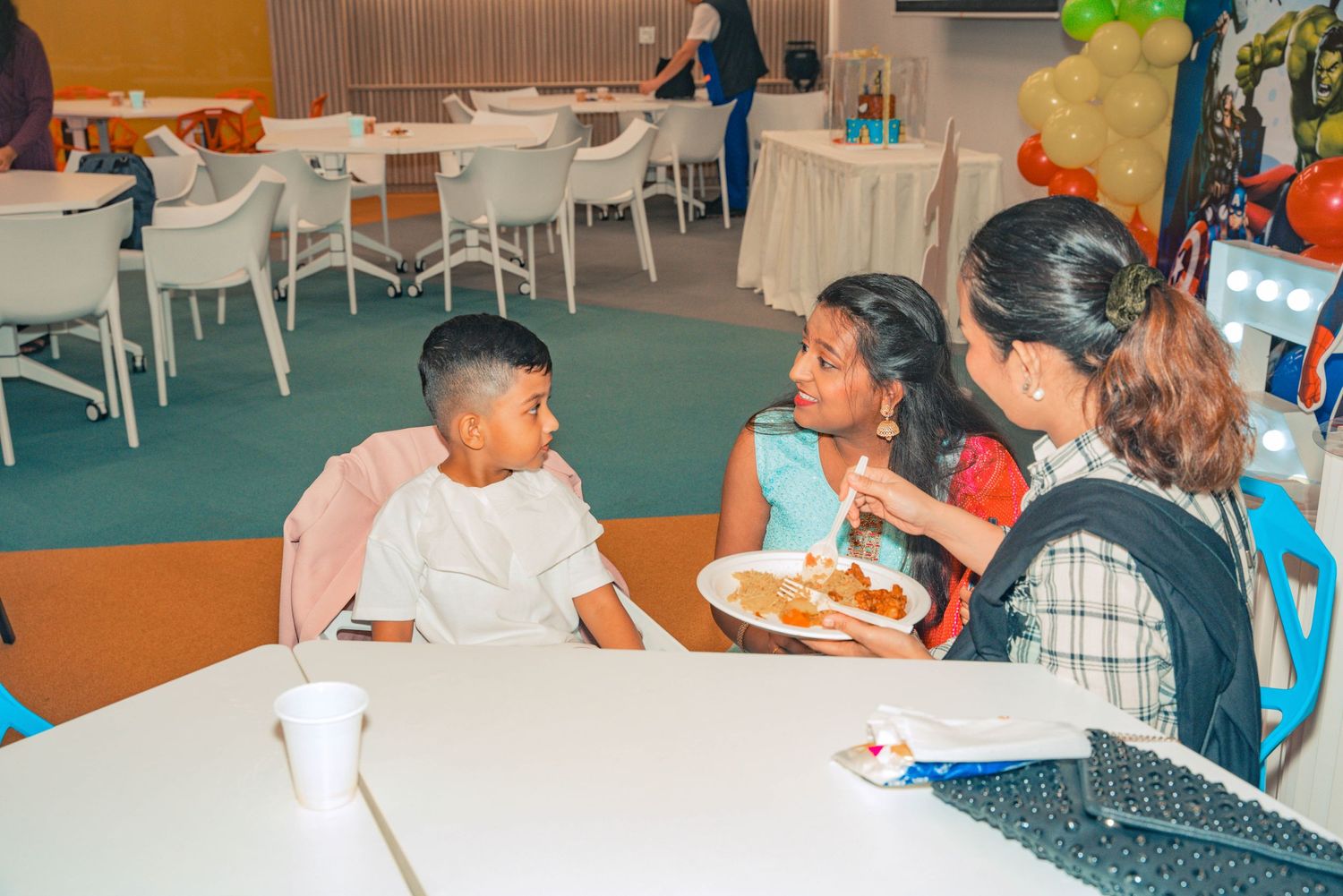 Children enjoying food at a party while seated at a round table.
