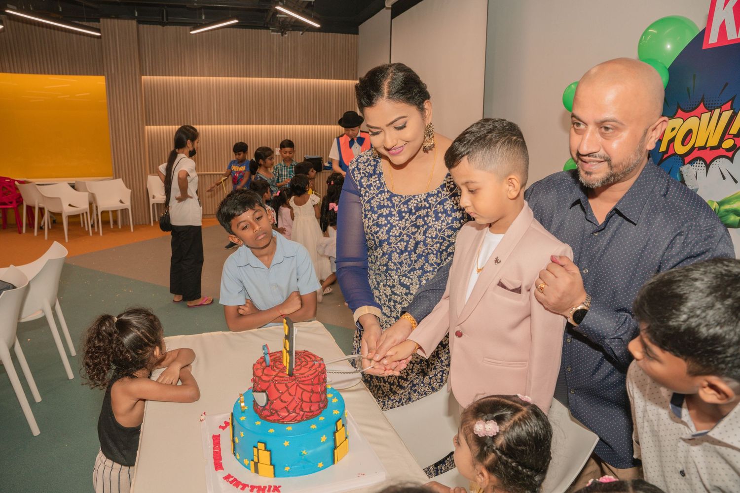 A family moment at a birthday party with a Spider-Man themed cake.