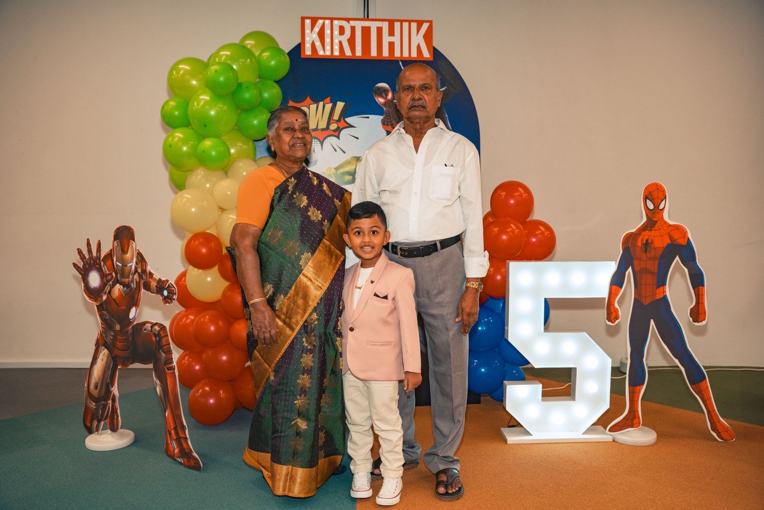 Family photo at birthday celebration with Spider-Man decor and balloon arrangement.