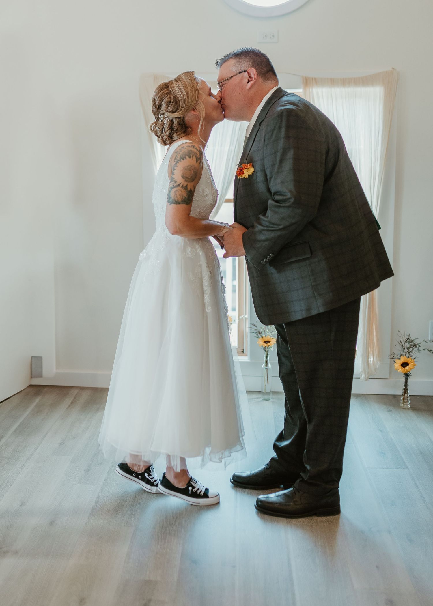 A tender moment between newlyweds in a bright indoor setting with hardwood floors.