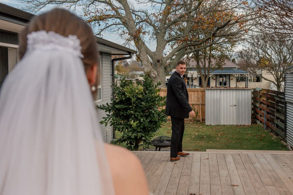 Wedding first look moment captured from behind bride looking at person on wooden deck Cambridge New Zealand