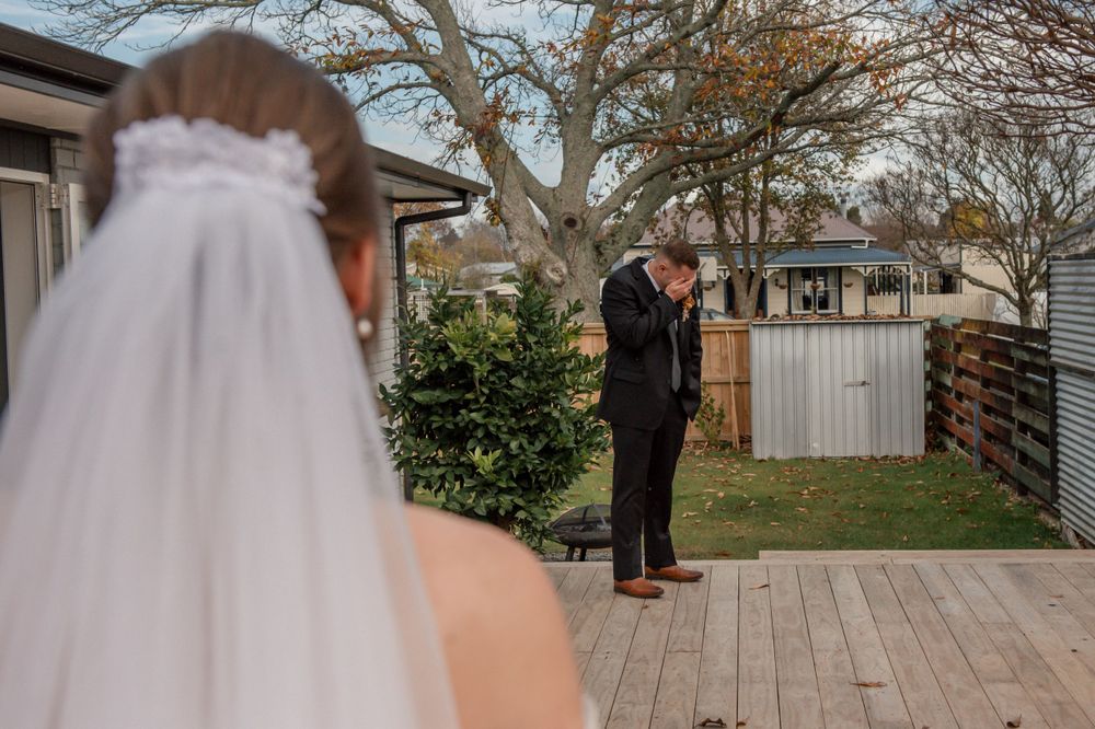 Two people share an emotional first look moment on a wooden deck during a wedding ceremony Cambridge New Zealand