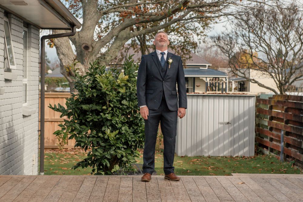 Formal portrait on wooden deck with green shrub and white fence in background Cambridge New Zealand