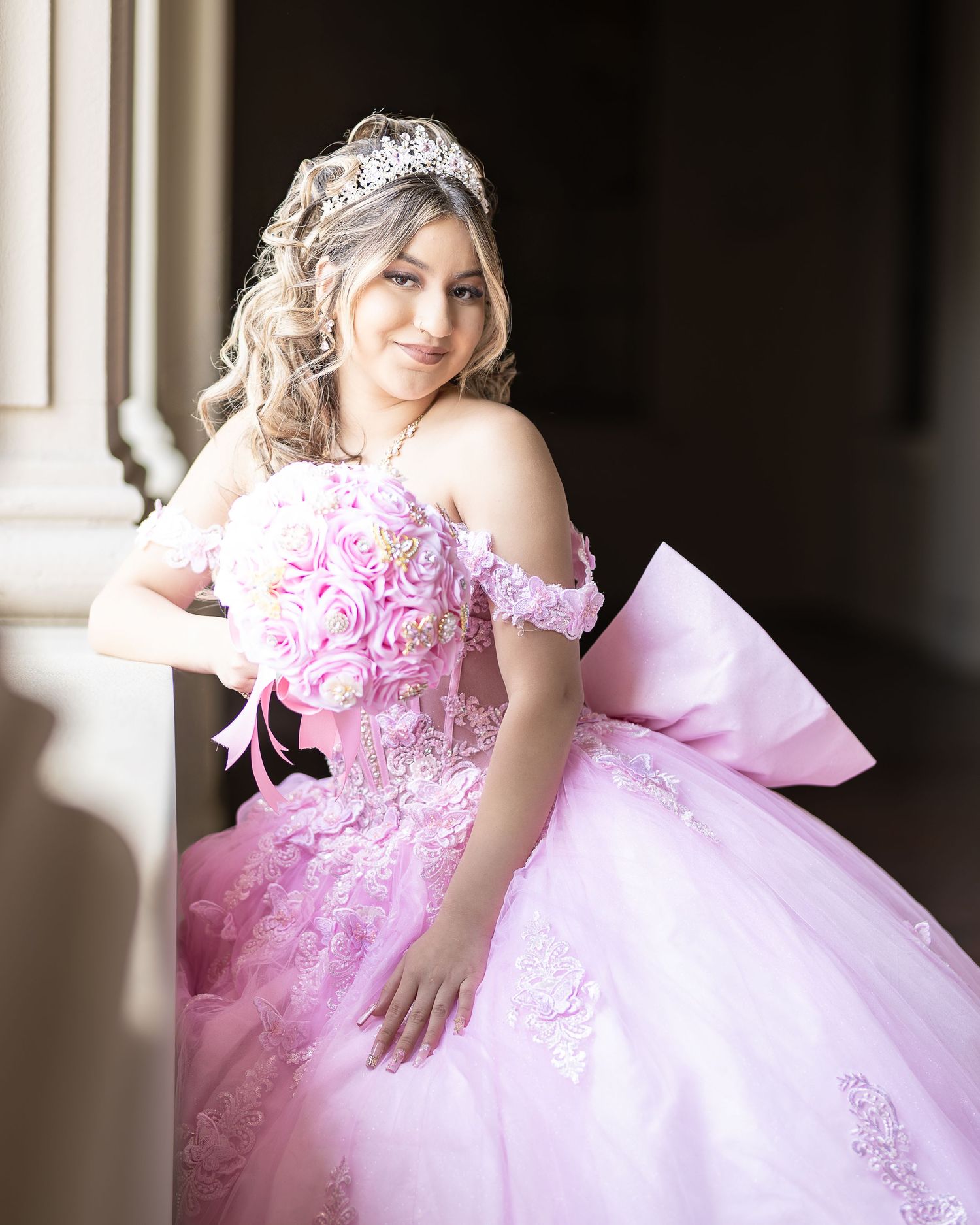 Quinceañera portrait of a girl wearing a pink dress. A professional photographer uses natural light to pose and photograph a Quinceañera.