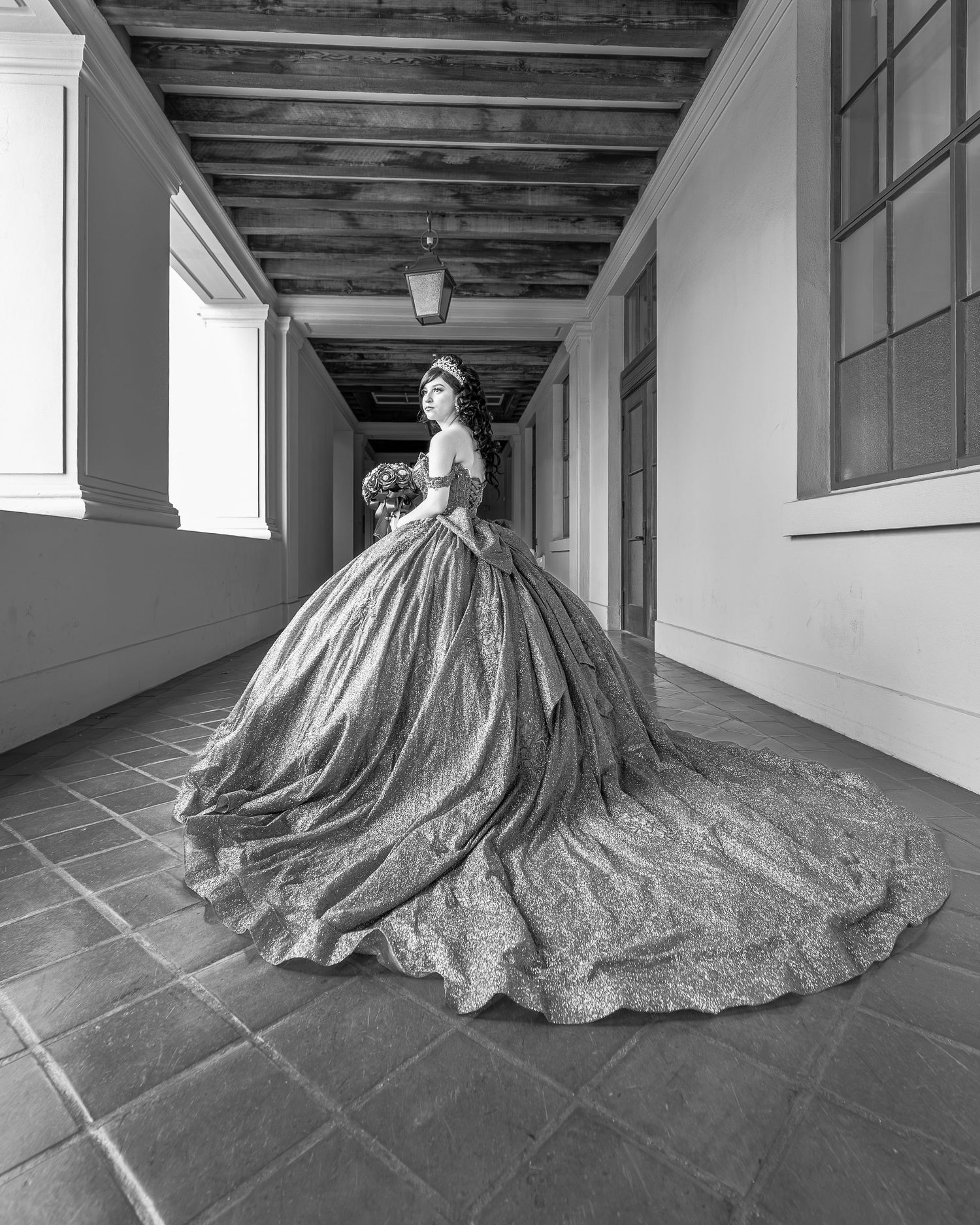 Black and White portrait of a quinceañera in a ball gown dress. Professional photographer poses quinceañera using natural lighting.