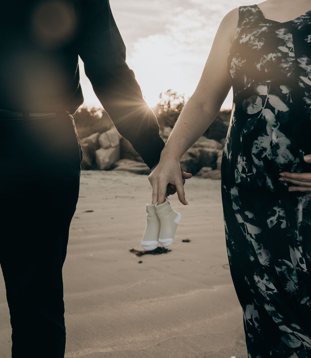 Couple dancing on a sandy beach at sunset with their shadows casting long silhouettes on the ground.