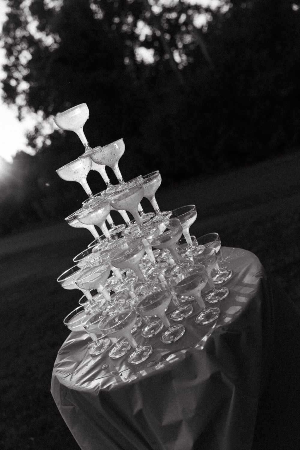 A black and white image of a champagne glass tower arrangement at a wedding reception.