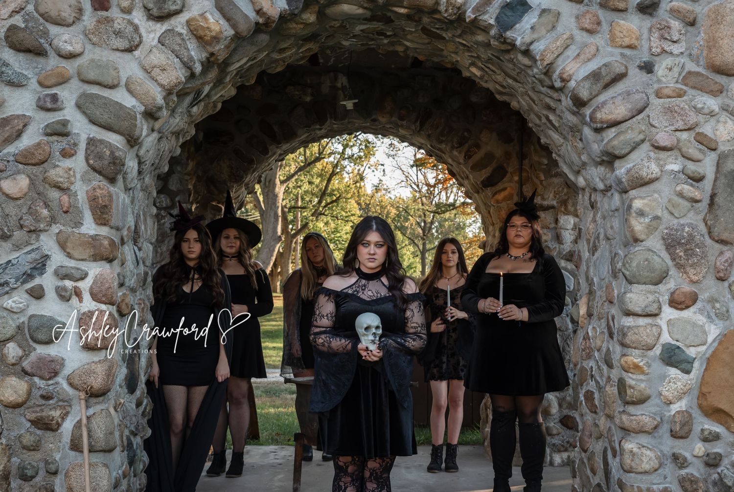 Gothic-styled group stands together beneath a rustic stone archway in natural lighting.