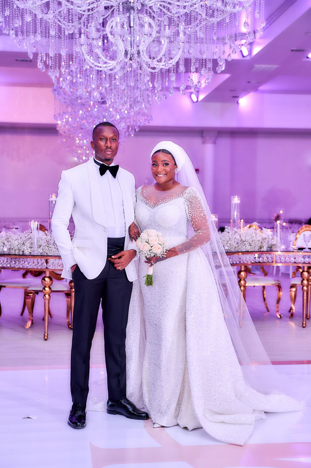 Elegant wedding reception venue with crystal chandelier and white decor.
