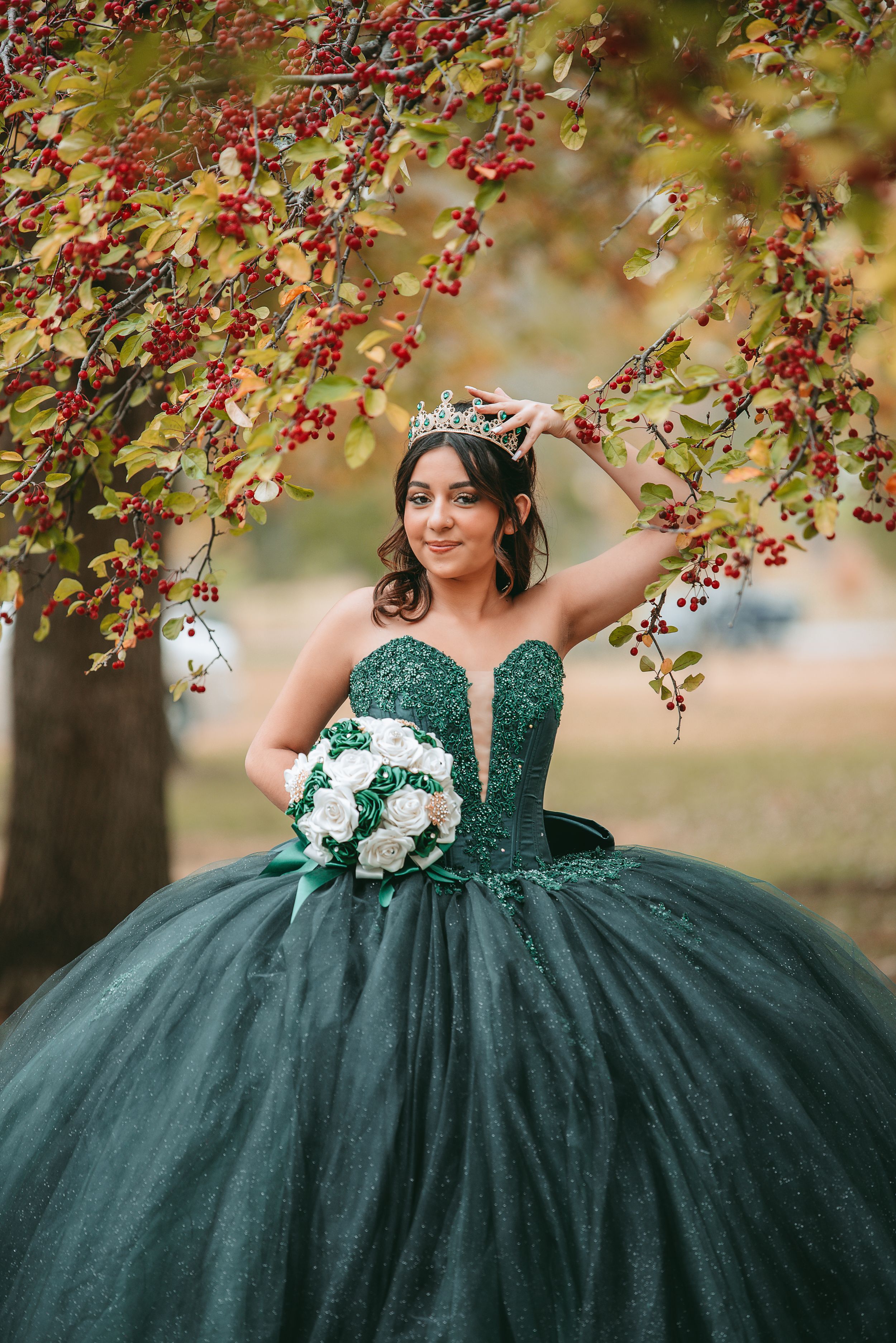 Emerald green ballgown photographed under autumn trees with red berries.