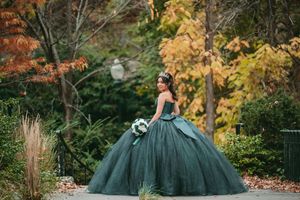 A stunning emerald green ballgown photographed against autumn foliage in an outdoor setting.