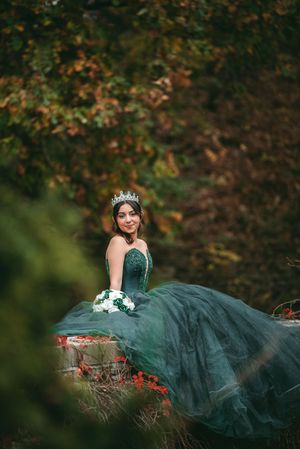 Dramatic emerald ballgown photographed in a natural woodland setting with fall colors.