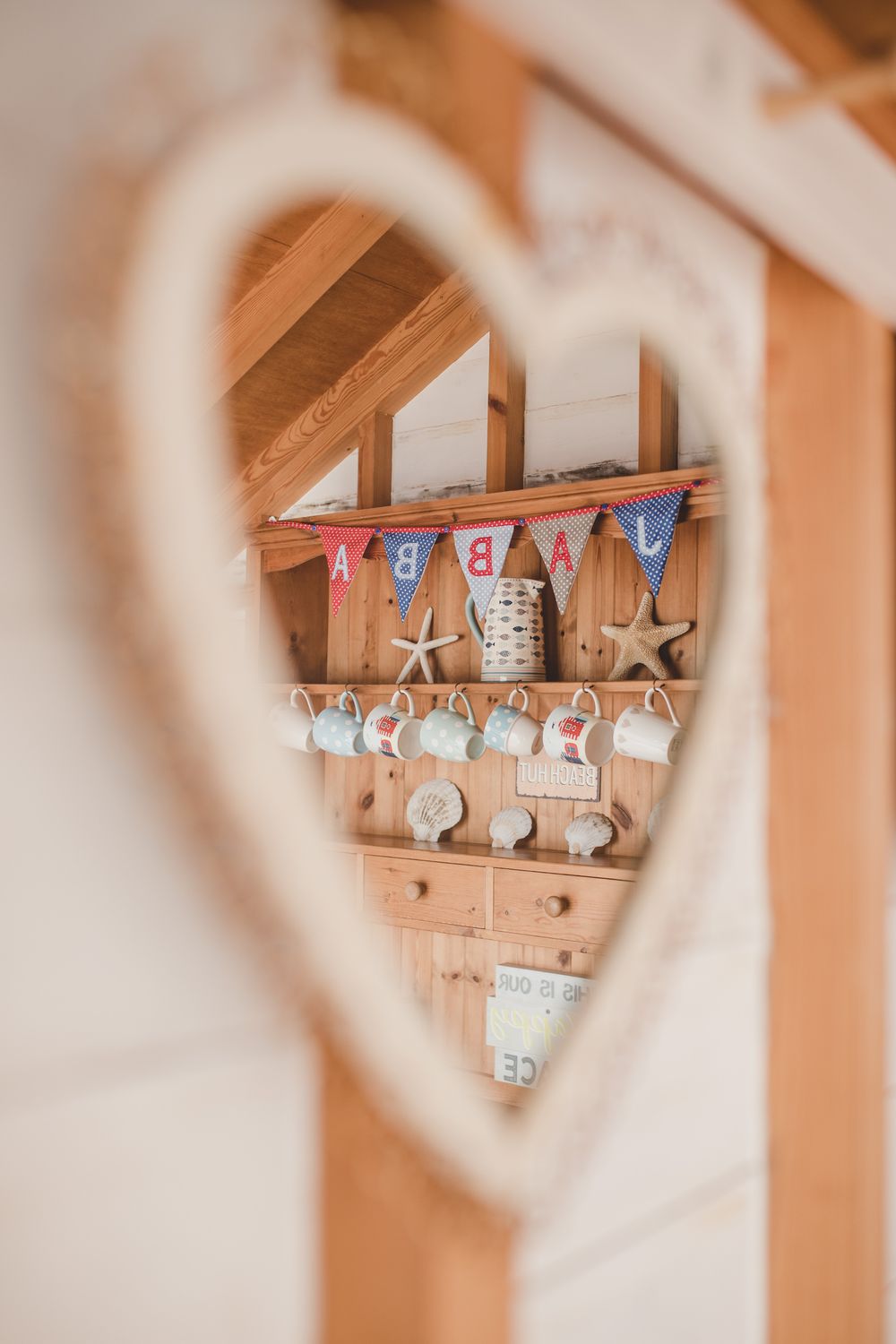 Heart-shaped view looking through to a rustic wooden shelf with 'BABY' bunting, stars and baby decor in warm tones.