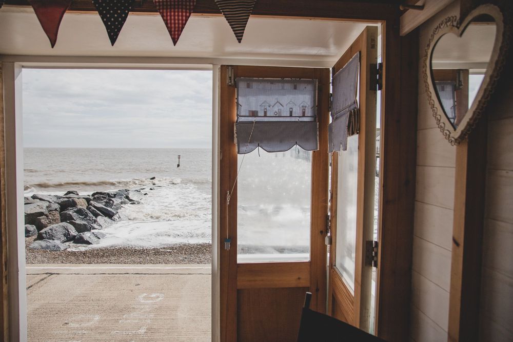 Interior doorway view looking out to a rocky beach coastline with bunting flags hanging above the entrance.