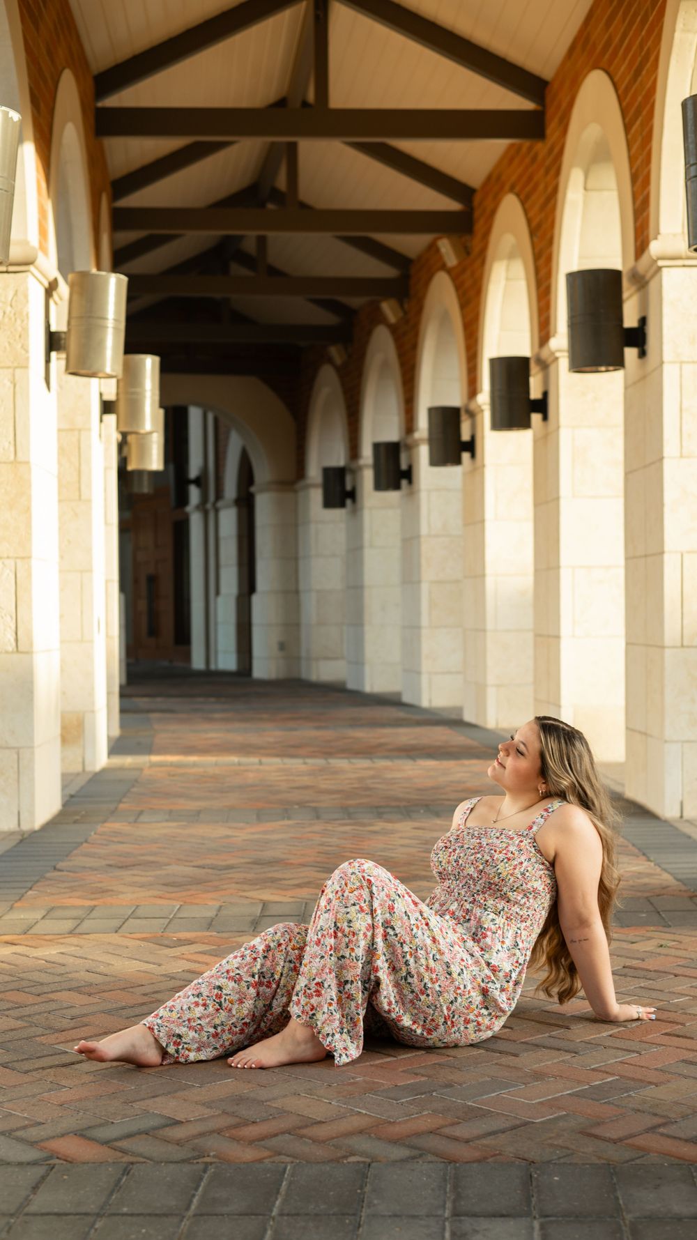 Floral maxi dress photographed against elegant stone archways and brick flooring in warm afternoon light.