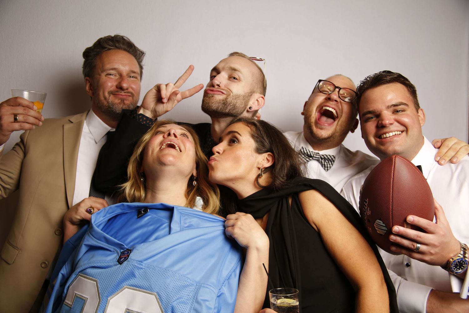 Group wearing sunglasses and hats pose together for fun photo booth portrait.