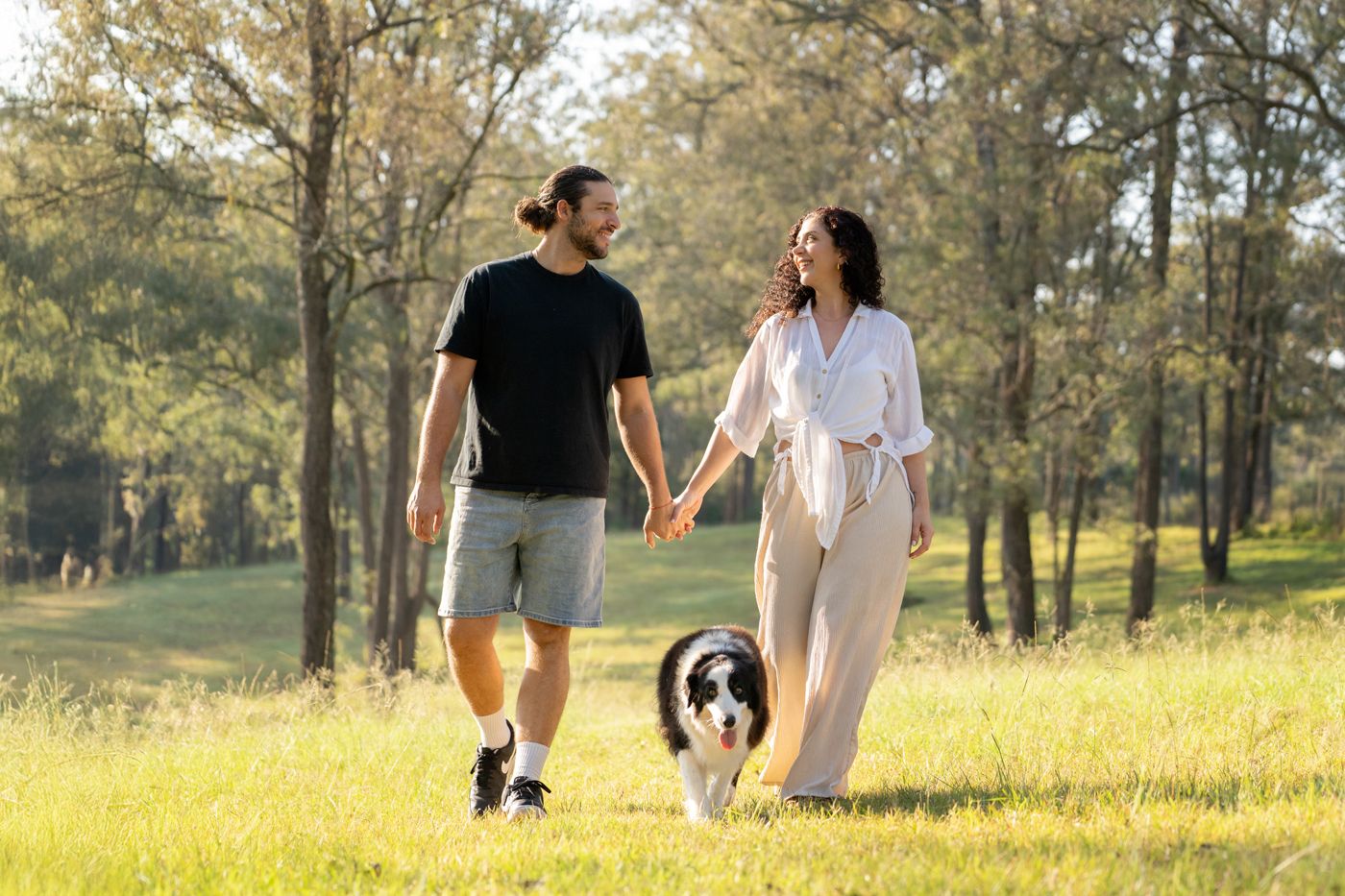 Cattai Sydney couples looking at each other walking towards the camera during a photoshoot with their dog