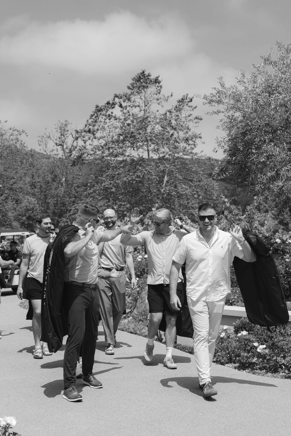 A group of wedding guests walking and celebrating together outdoors in black and white.