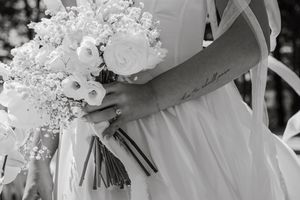 Black and white close-up of an elegant white wedding bouquet with roses and baby's breath.