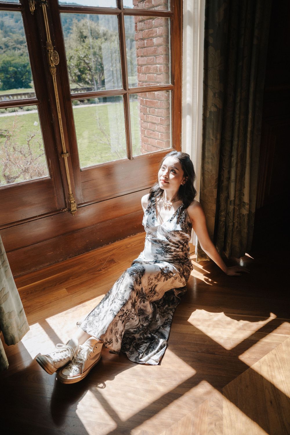 Sunlight streams through large windows onto hardwood floors in a vintage-style room.