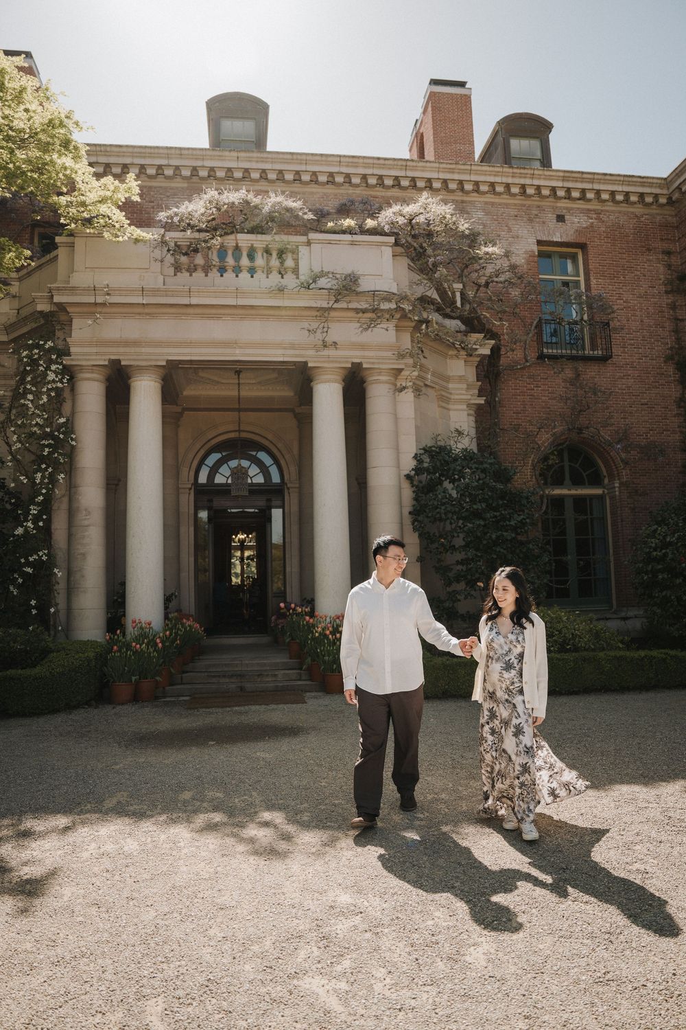 Classic architecture with white columns and brick walls surrounded by spring blossoms.