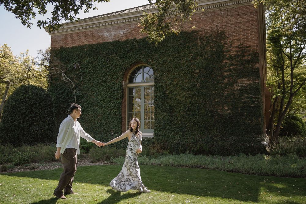Romantic outdoor scene of couple dancing in front of brick building with ivy covered walls.