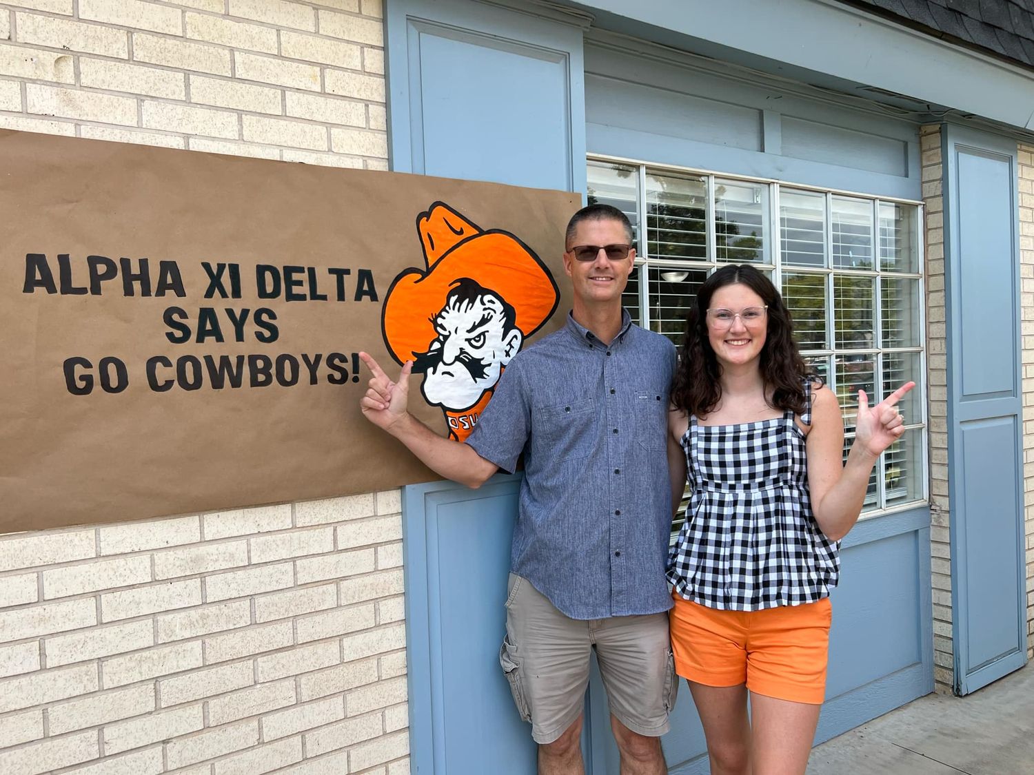 Summer Judd and her dad standing by her first hand painted banner.