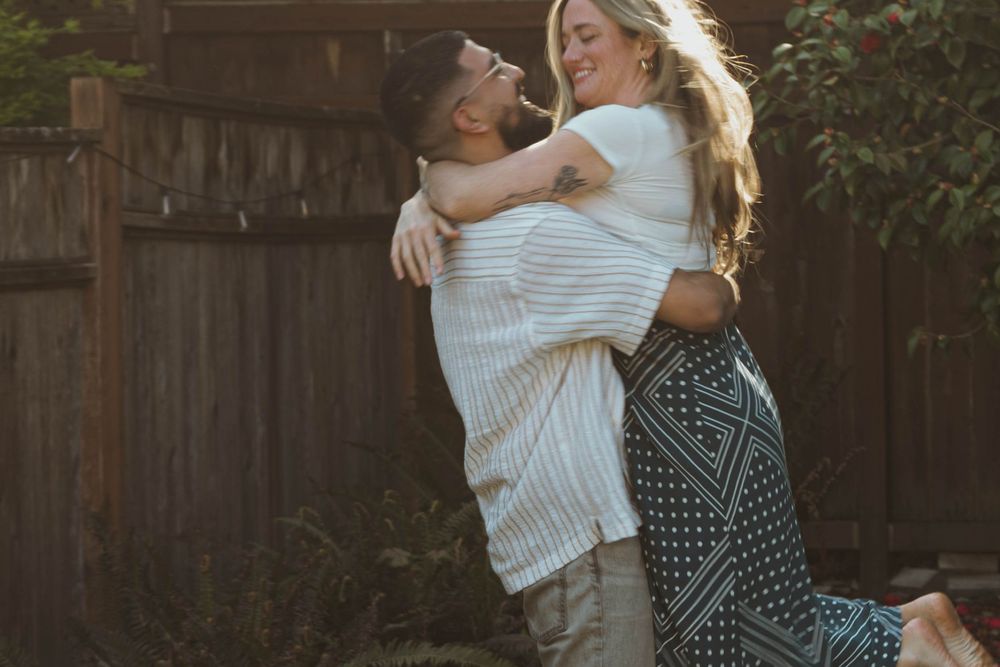 A couple embraces in a backyard during golden hour.