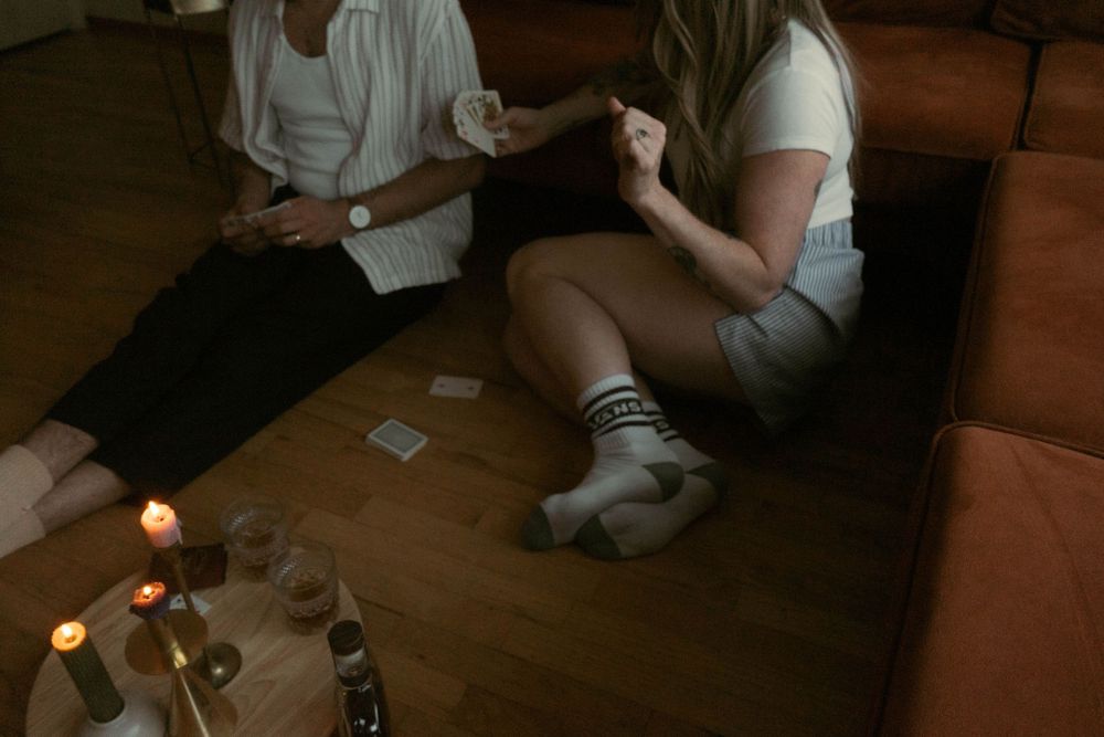 Casual game night scene with playing cards and candles on wooden floor.
