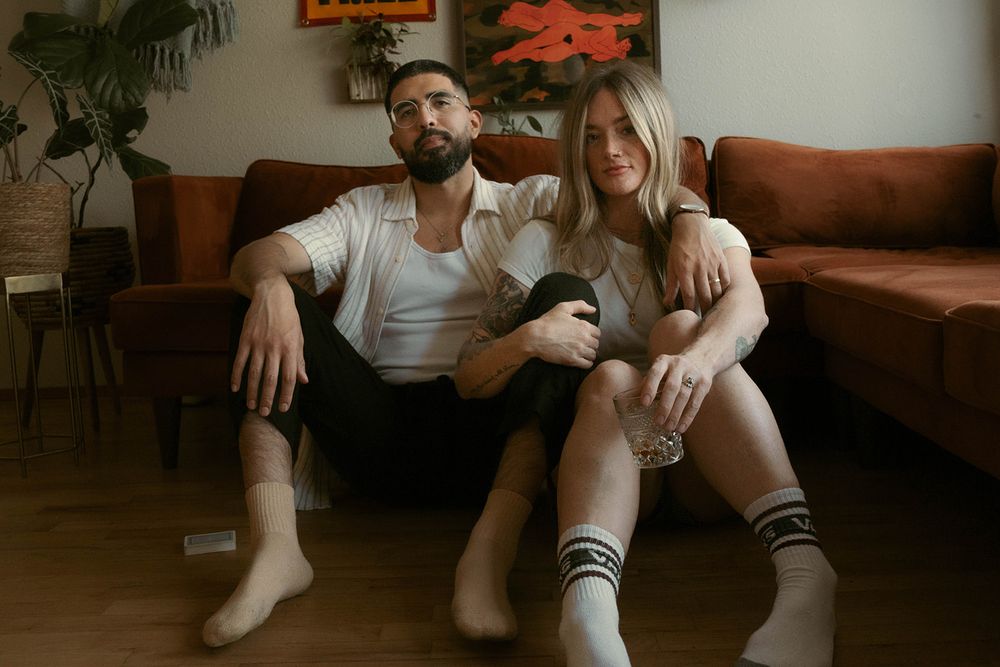 Intimate portrait of couple relaxing on brown leather couch in living room.