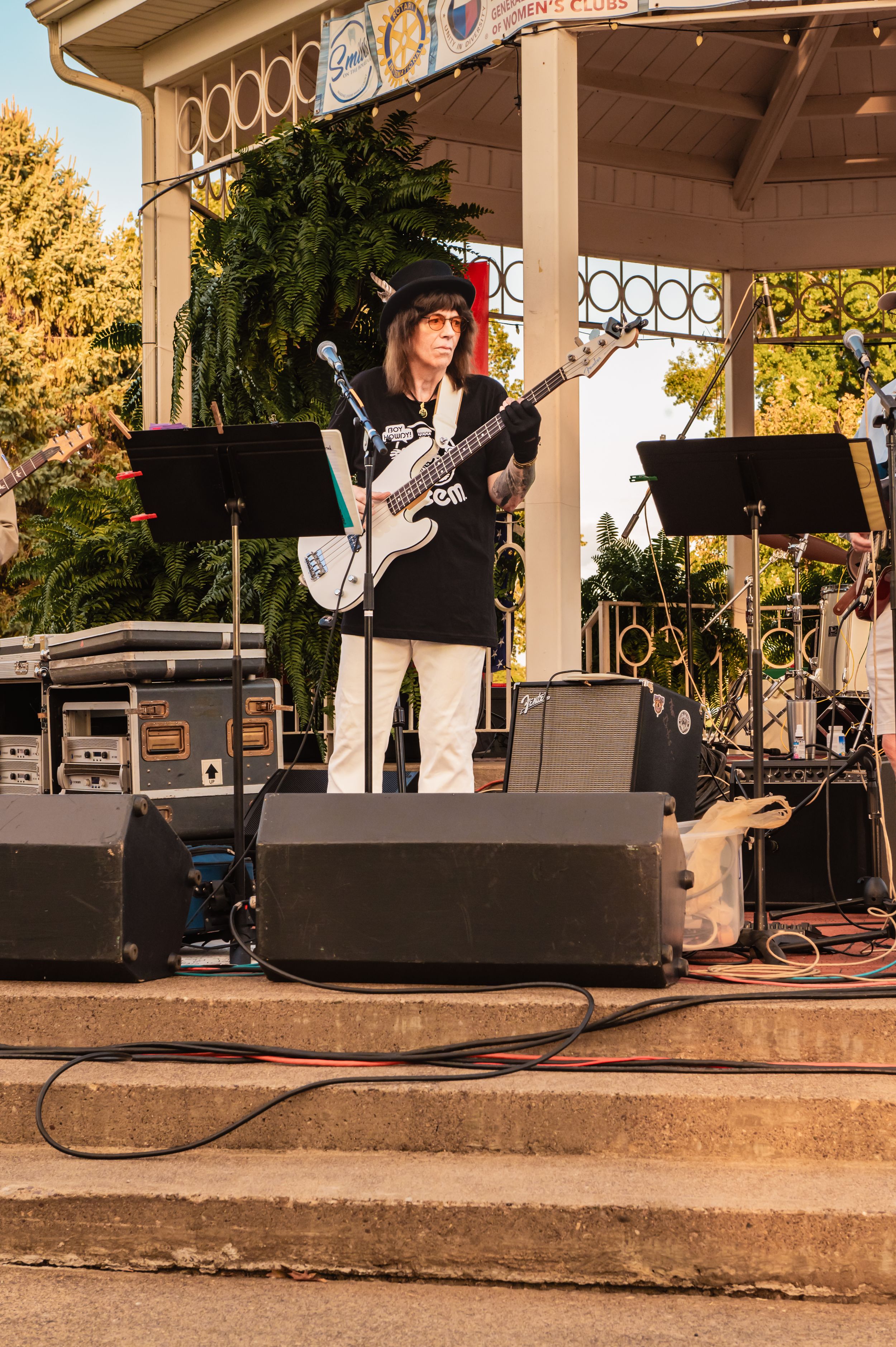 Outdoor stage setup with audio equipment and musicians performing at a bandstand.