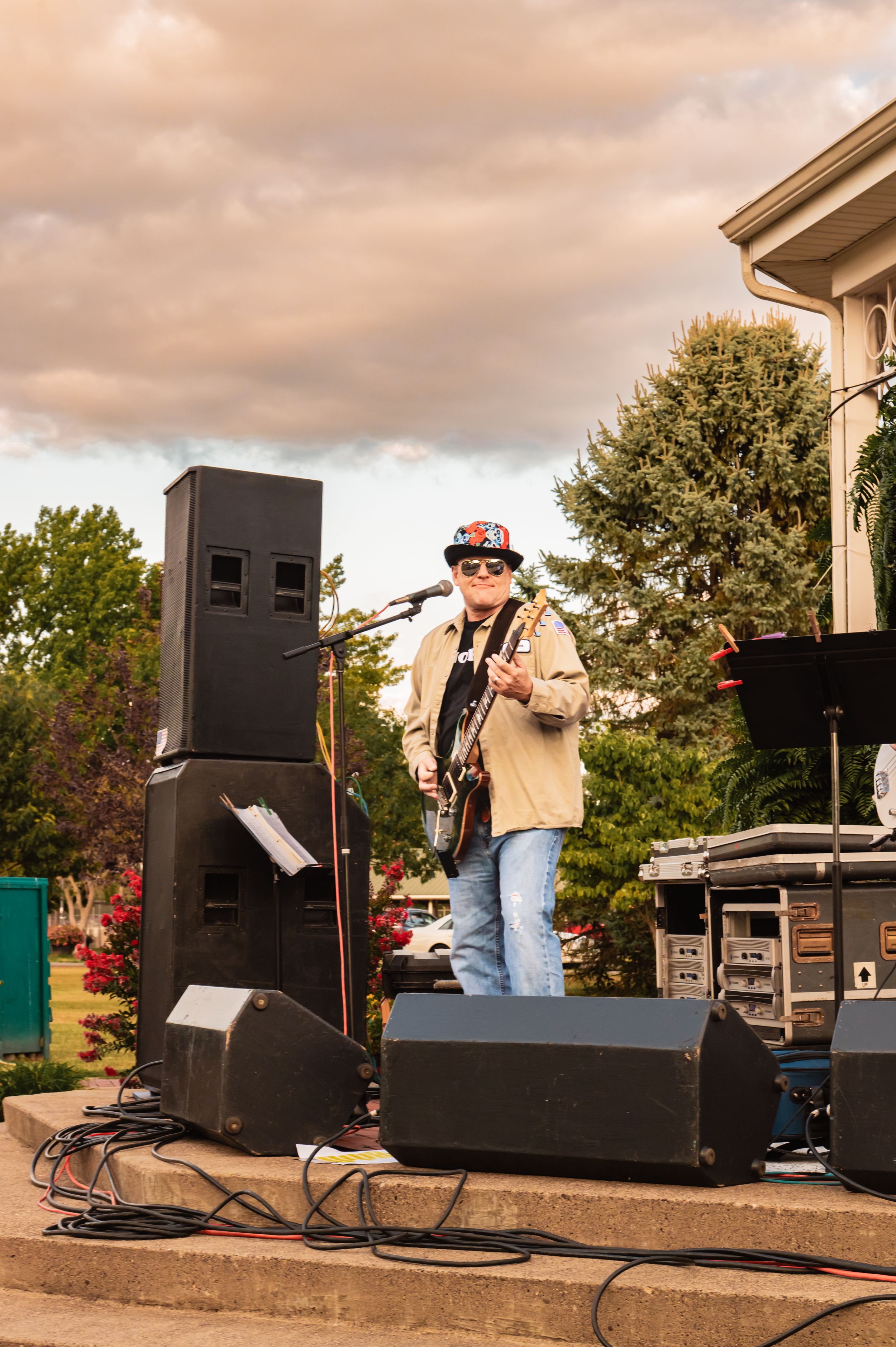 Outdoor concert setup with large speakers and musicians on stage during sunset.