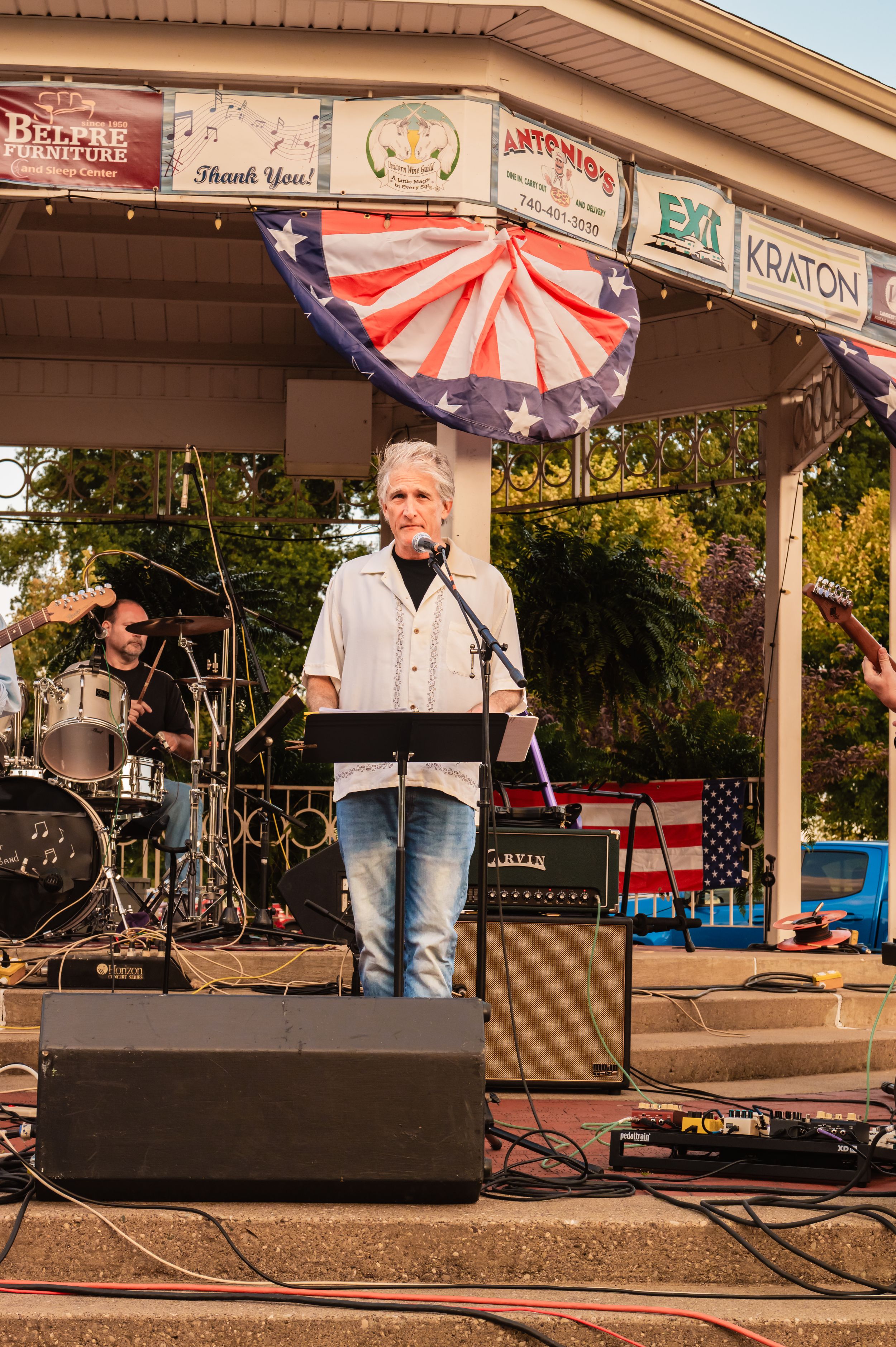 Musicians performing under a covered pavilion with American flag decorations.