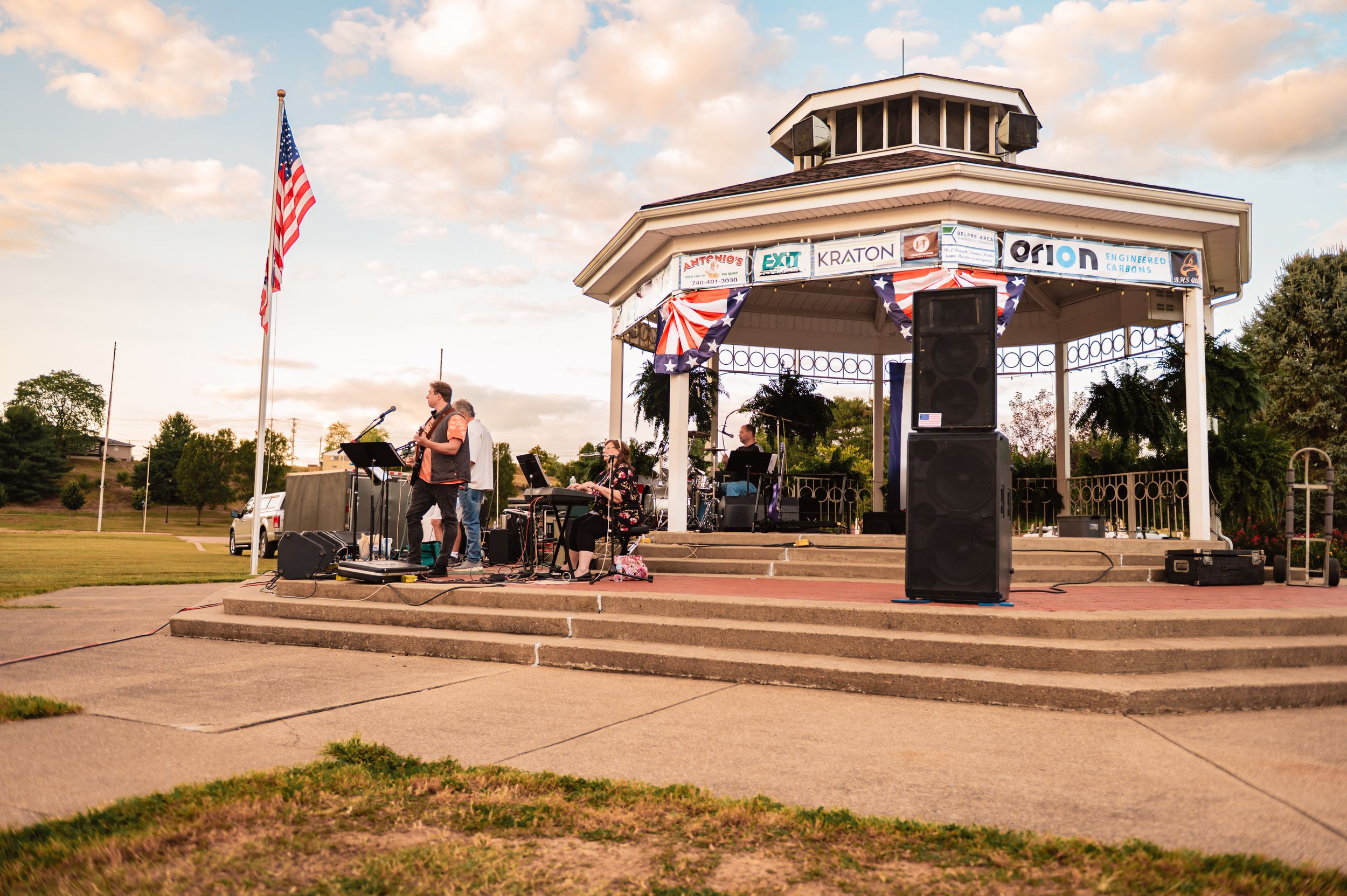 Panoramic view of an outdoor venue with American flags and concert setup.