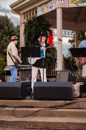 Performers entertain on decorated gazebo stage during outdoor music event.