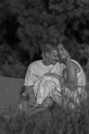 Intimate black and white portrait of couple resting in tall grass.