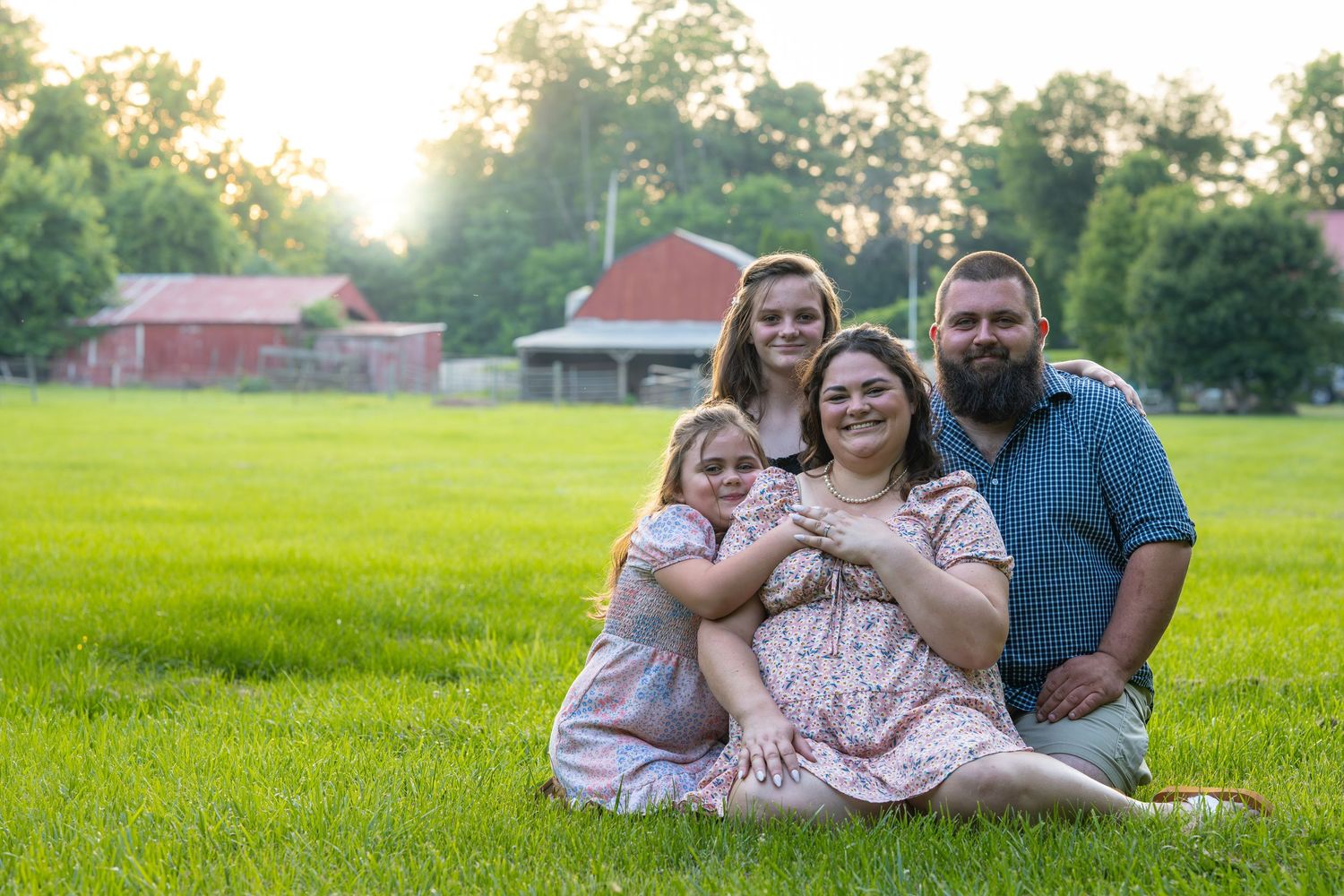 A couple relaxes together in a sunny meadow during a summer photo session.