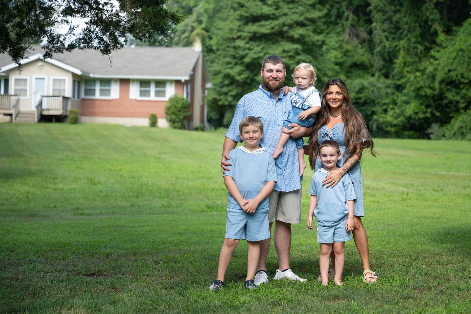 A family group poses together on their front lawn for outdoor portraits.