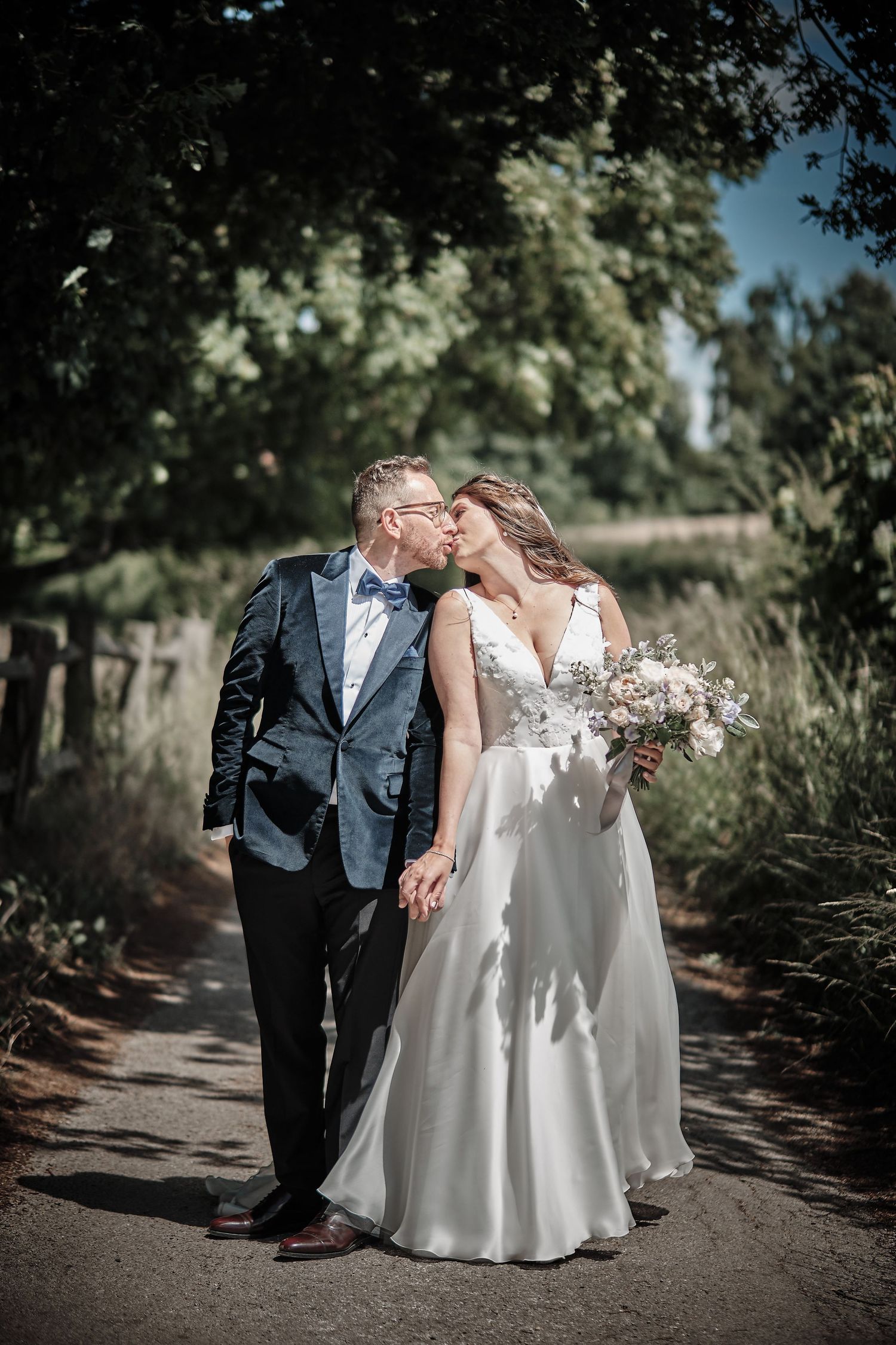 A romantic wedding couple shares a tender moment on a sunlit garden path as they celebrate their special day.