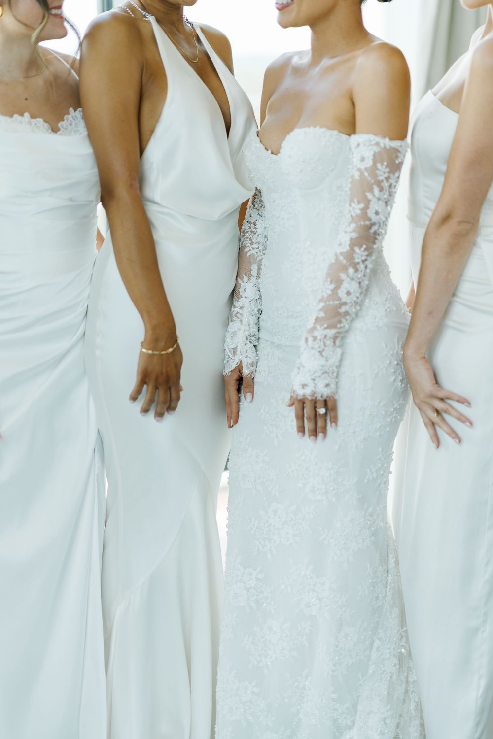 Close up view of elegant white wedding dresses showing variety of styles including lace sleeves and fitted silhouettes.