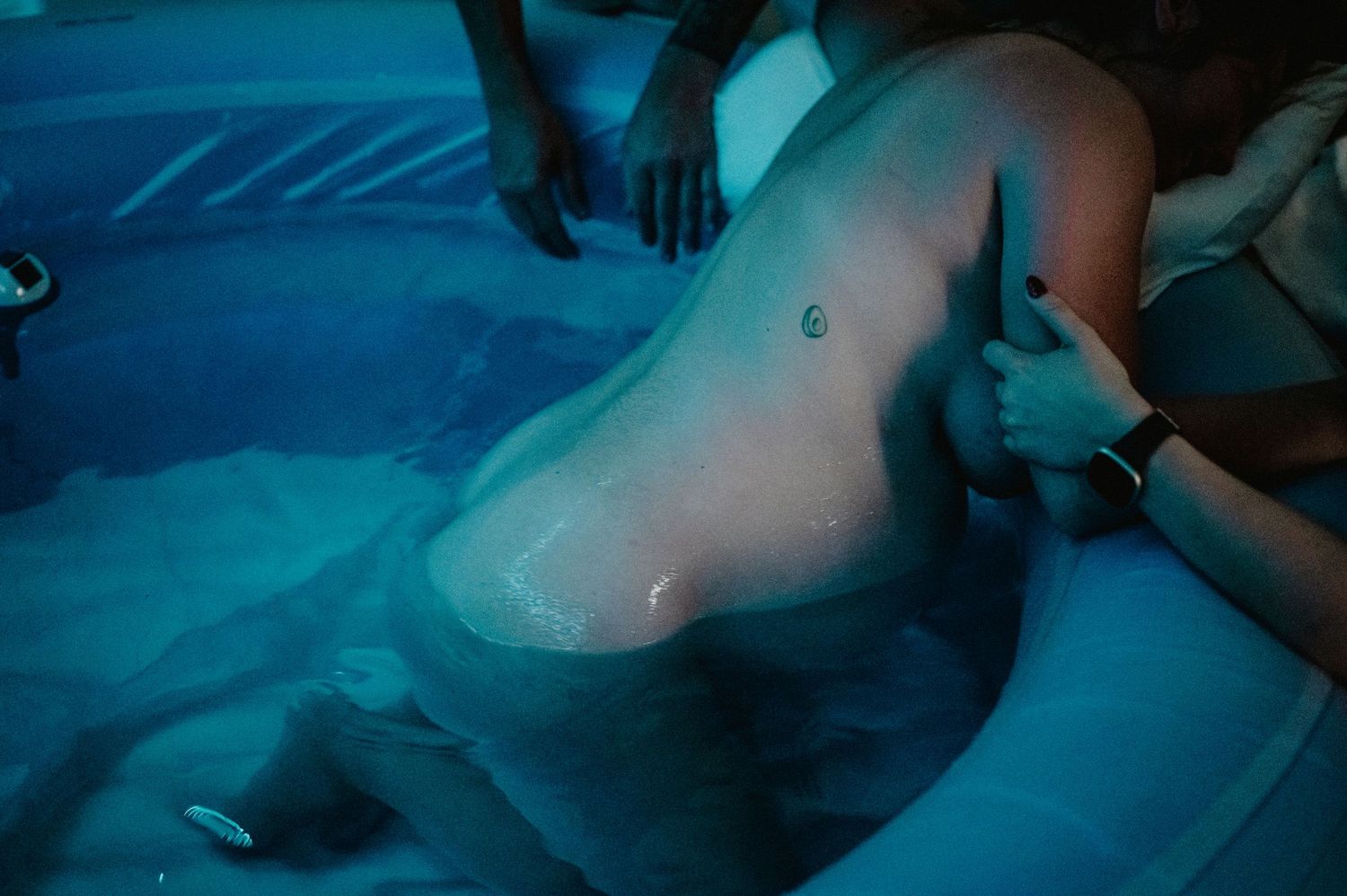 Aqua-colored lighting illuminates someone receiving a relaxing therapeutic massage treatment on a table.