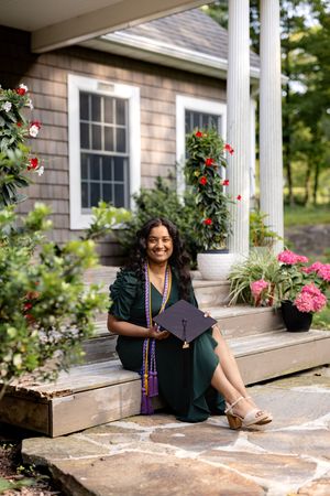 Three outdoor graduation photos taken on a rustic porch with white columns and colorful rose bushes in the background.
