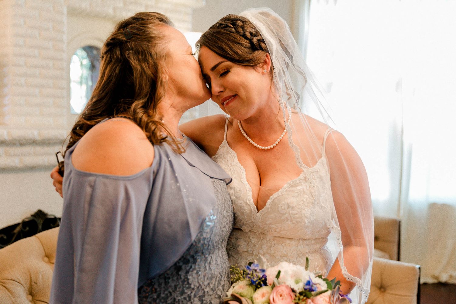 Bride and mom share an intimate moment while standing together when the bride is getting ready for the wedding.