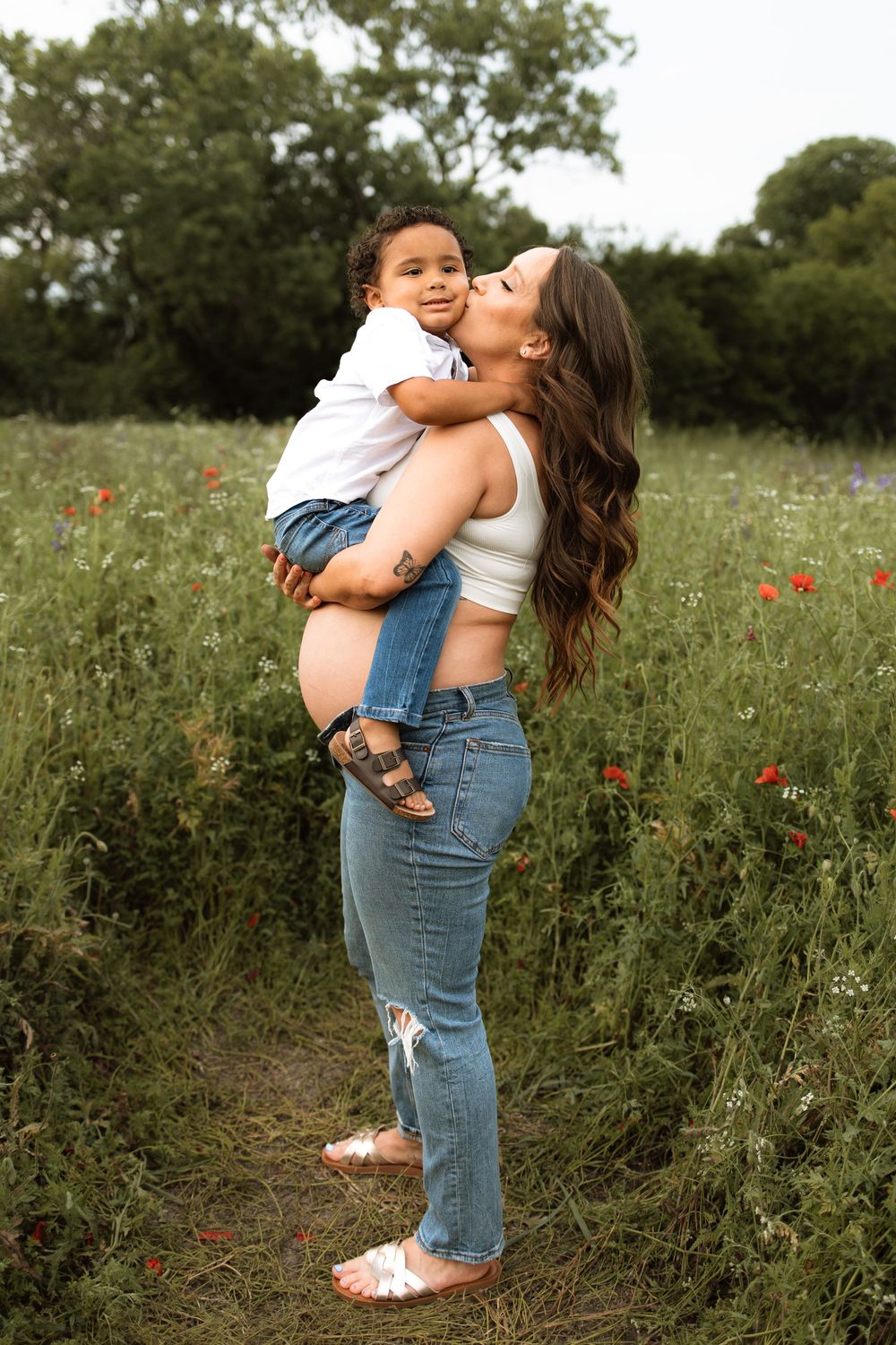 A tender moment captured in a wildflower meadow with red poppies as a parent lifts and embraces their child.