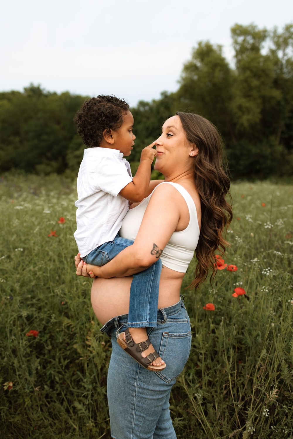 Sweet interaction between parent and child while standing in a summer meadow with scattered red wildflowers.