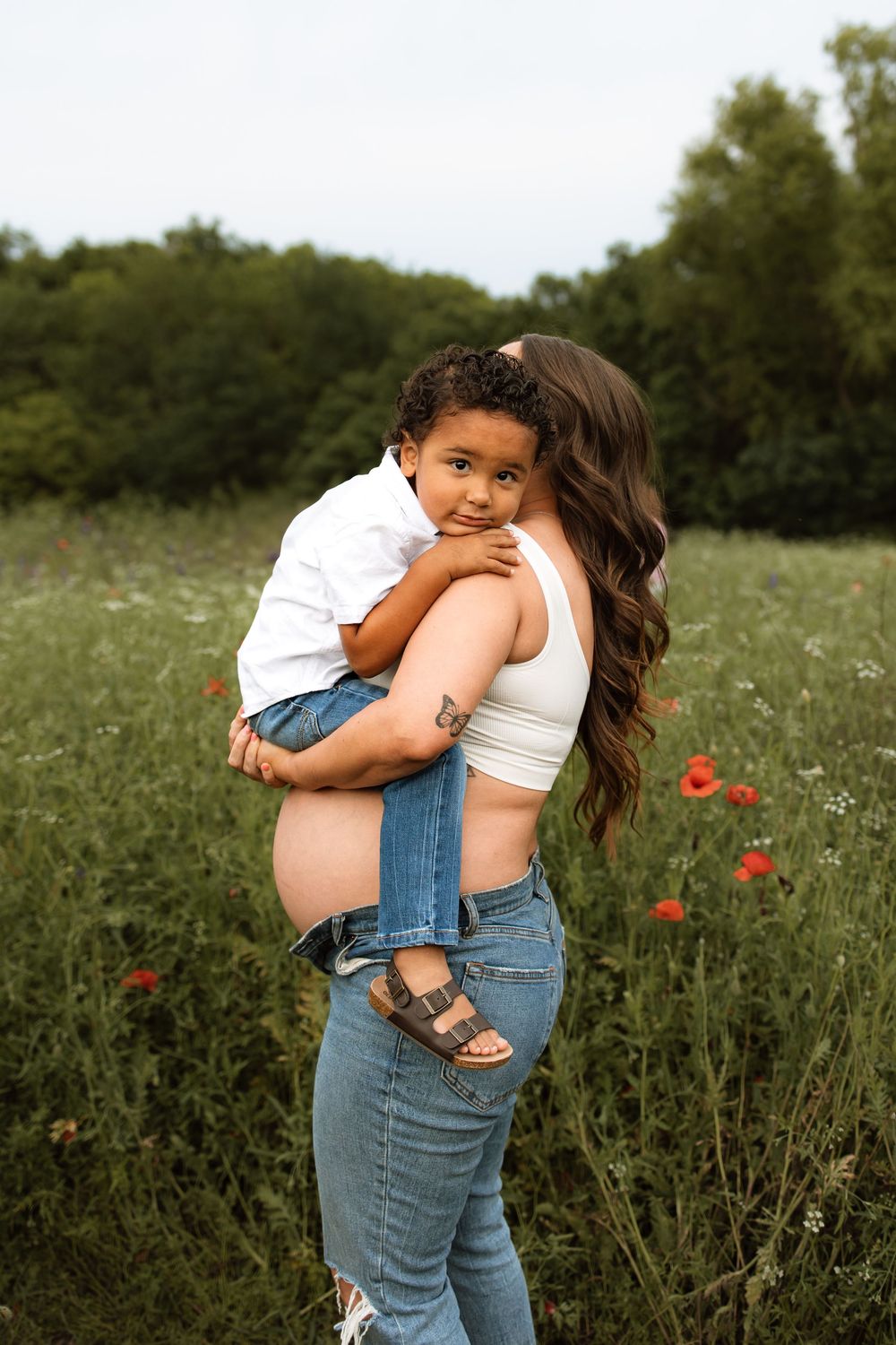 A tender moment shared between parent and child in a wildflower meadow with red poppies on a sunny summer day.