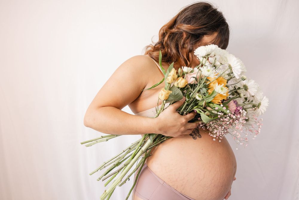 Artistic maternity photos with bouquet of yellow flowers against white background.